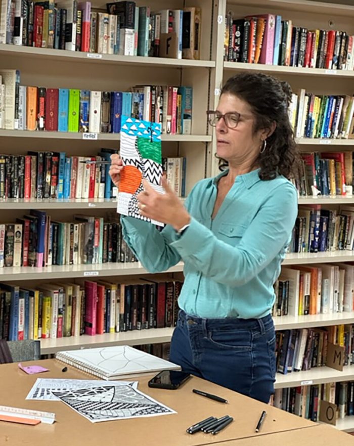 art instructor holding up paper with different types of colored areas for contrasting purposes